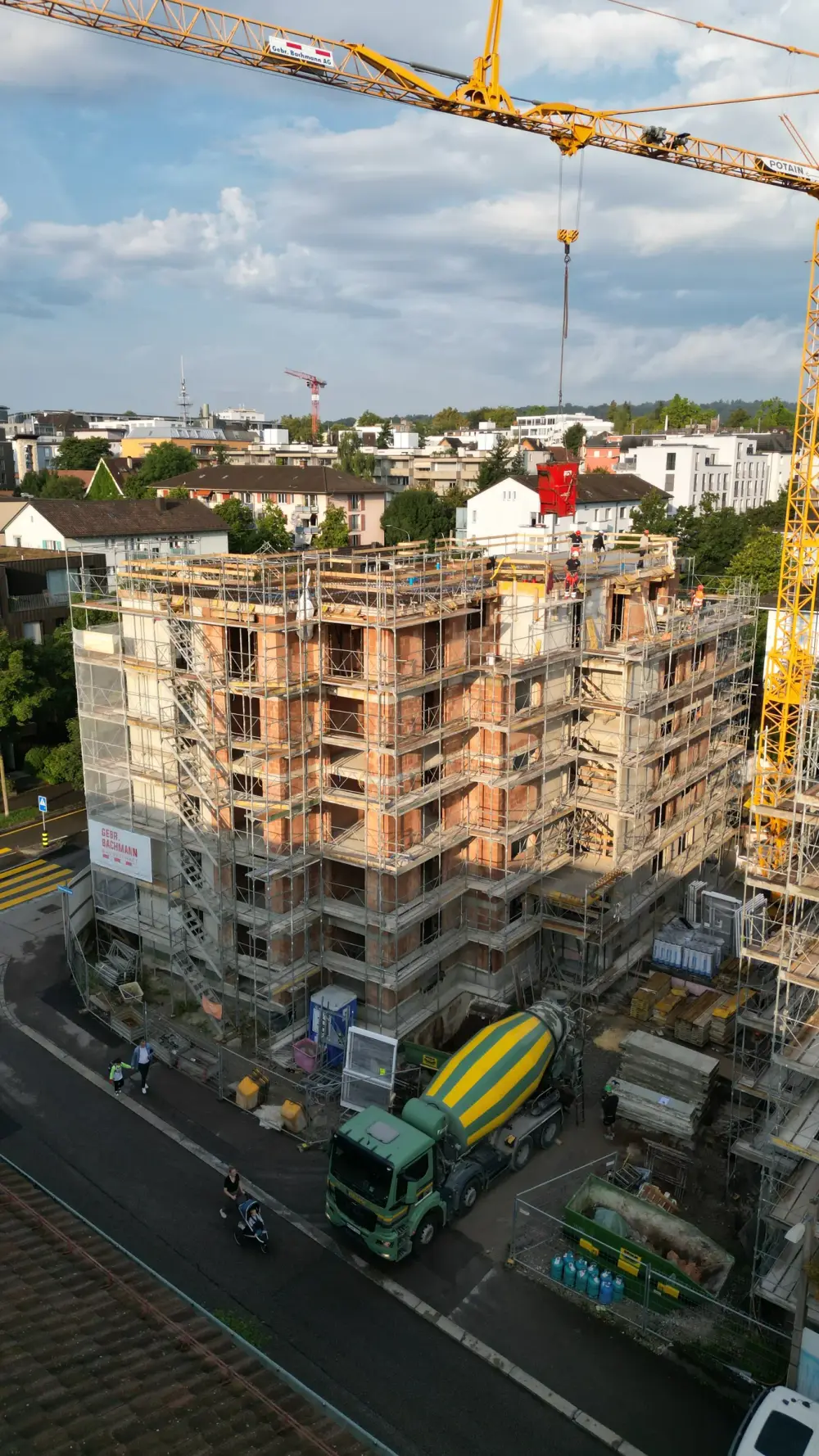 Luftbild: eingerüsteter Rohbau eines Mehrfamilienhauses mit Kran