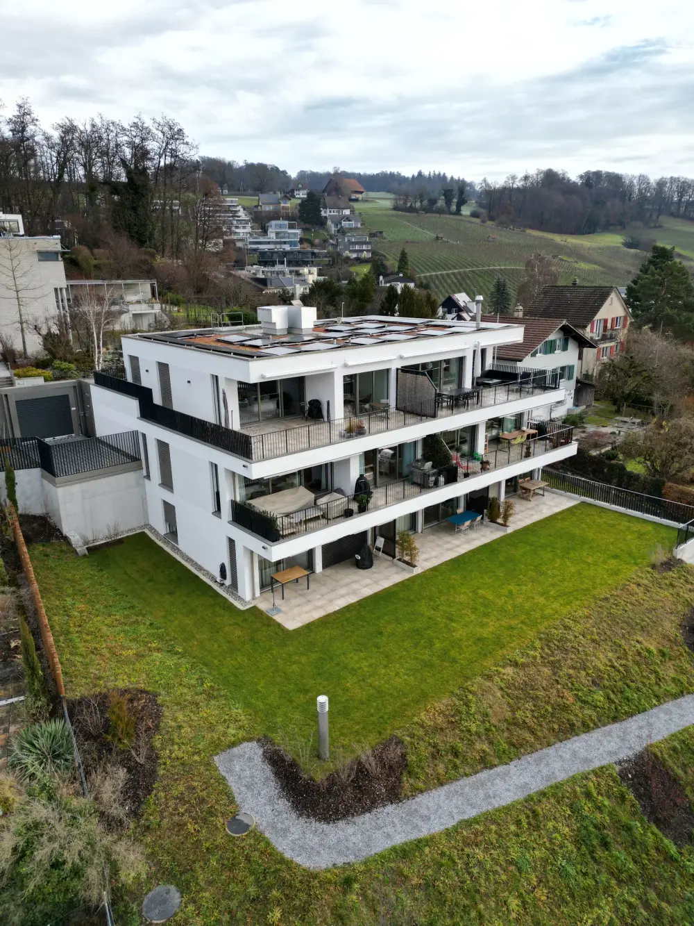 Fertige Umgebung mit Rasen und Sitzplatz rund um einen Neubau