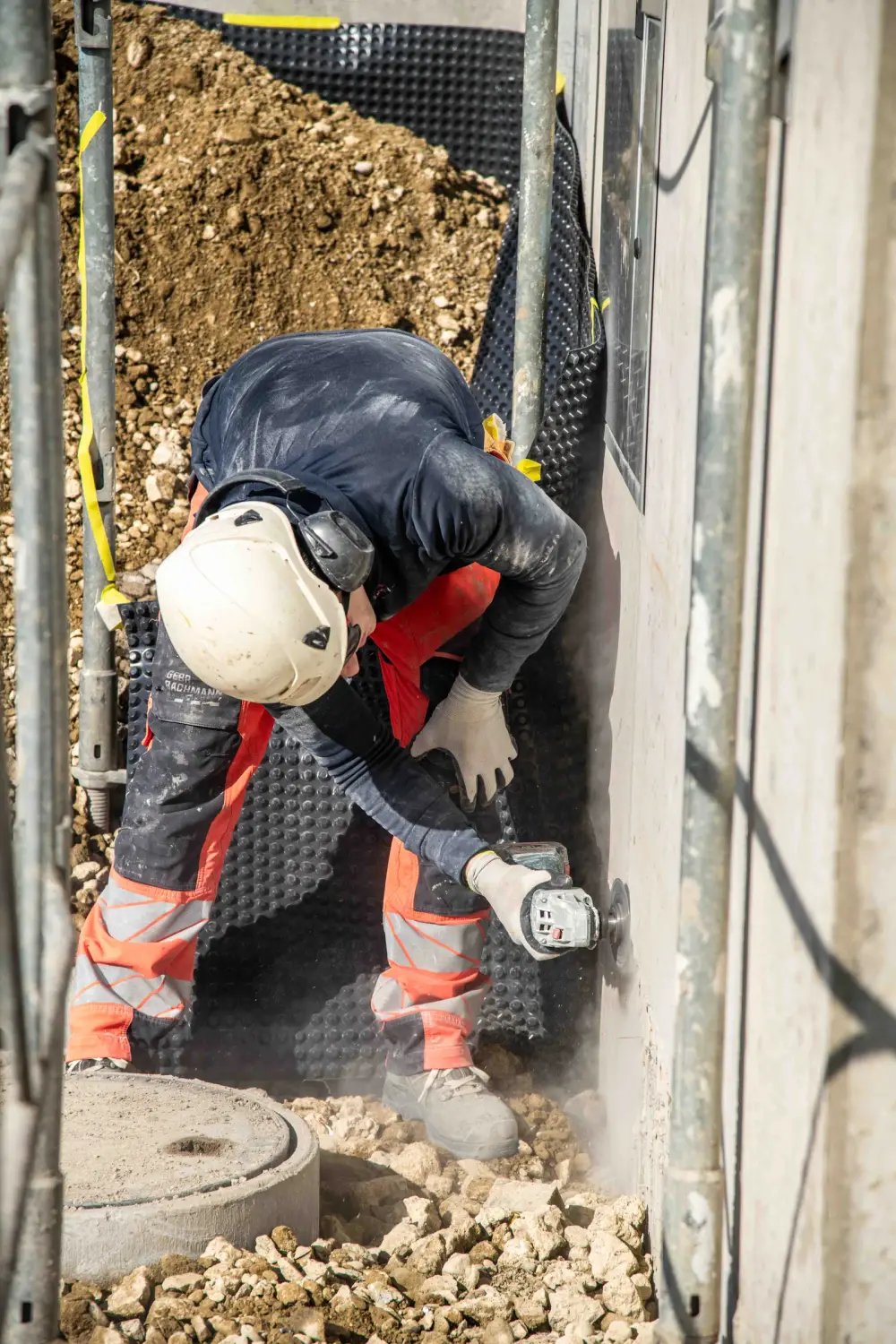 Mitarbeiter montiert eine Noppenbahn an der erdberührten Betonwand